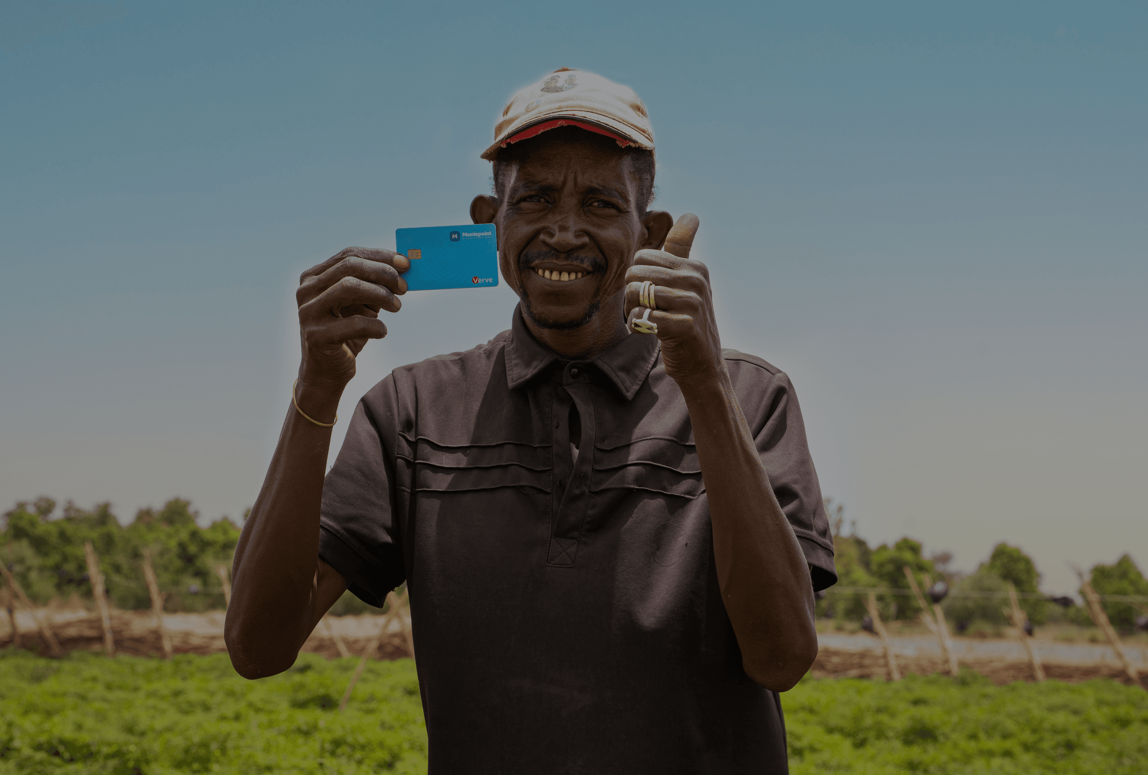 A Moniepoint customer holding a Moniepoint card in a green field